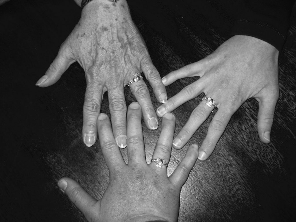 The hands of 3 women, each wearing a Claddagh Ring